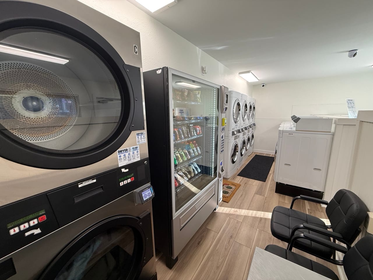 Community laundry room with stacked dryers, washing machines, snack vending, and seating